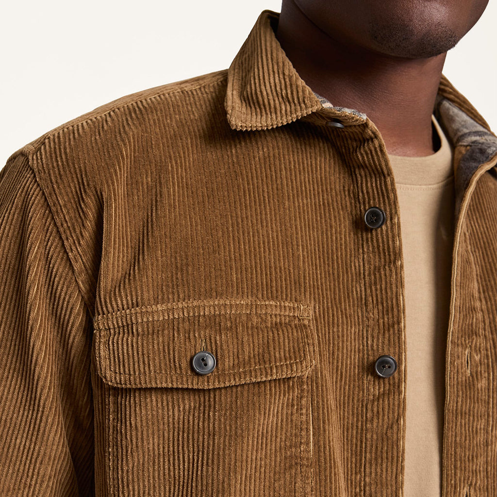Brown corduroy jacket with a pocket and buttons on a neutral background