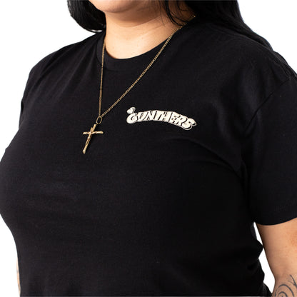 Person wearing a black t-shirt with 'Gunthers' logo and a gold necklace with a cross pendant.