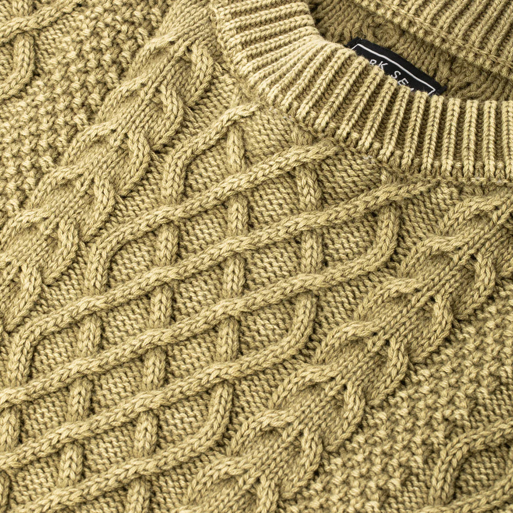 Close-up of a moss green knitted sweater with a brand label.