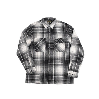 A long-sleeve plaid button-up shirt in black, white, and gray, featuring two large patch pockets on the front, displayed flat against a solid white background.