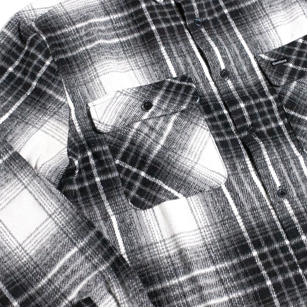 Close-up of a black and white plaid flannel shirt with a chest pocket and button closure.