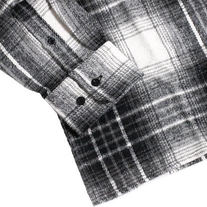 Close-up of a black and white plaid flannel shirt showing the buttoned cuff and fabric texture.