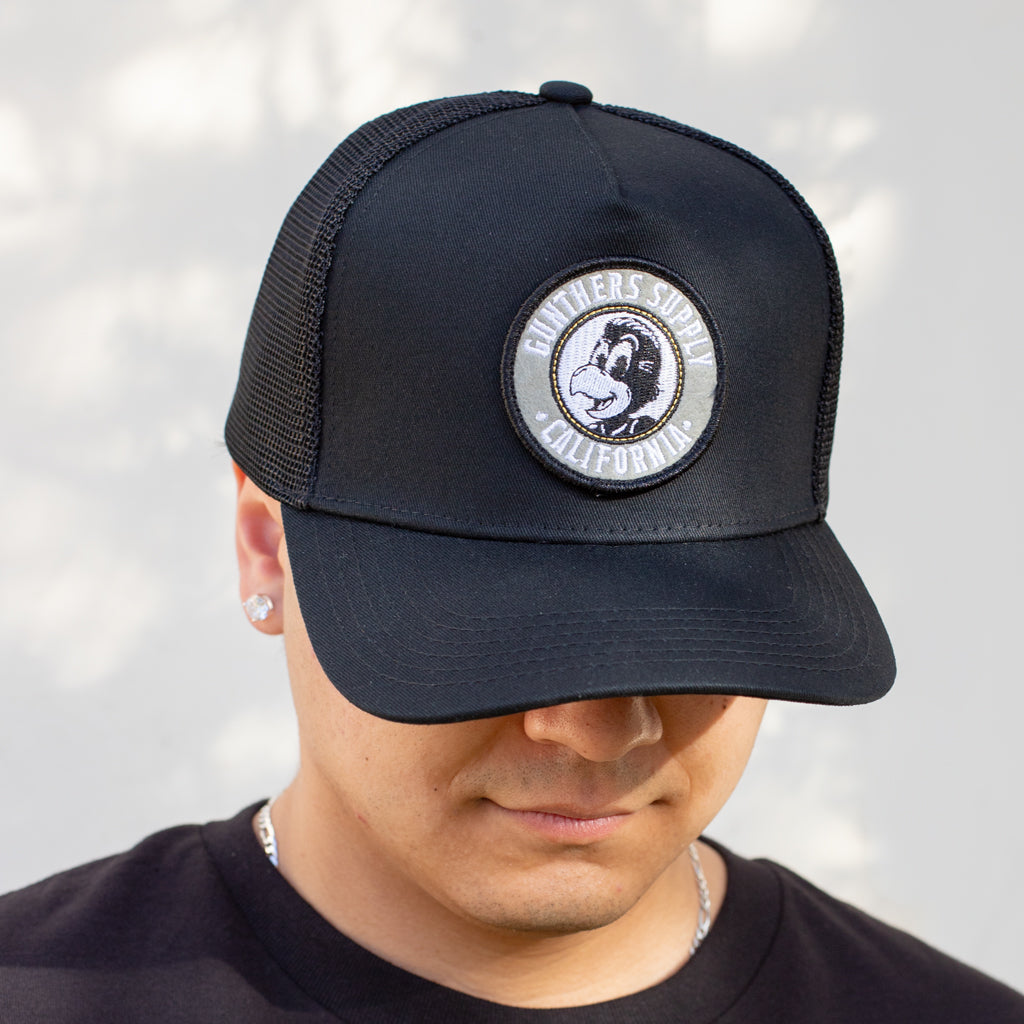 Black cap with a logo worn by a person against a light background