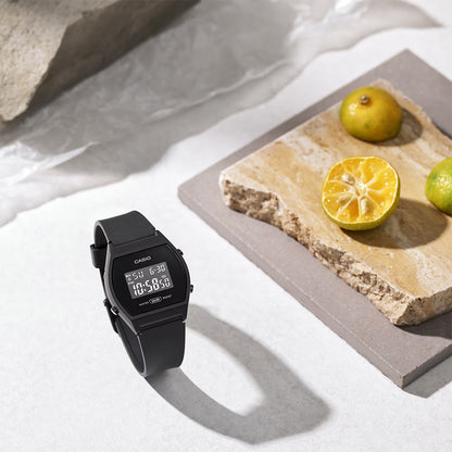 Black Casio digital watch on a light surface with a stone slab and lemons in the background