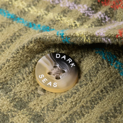 Close-up of a button with 'Dark Seas' branding on a textured fabric background