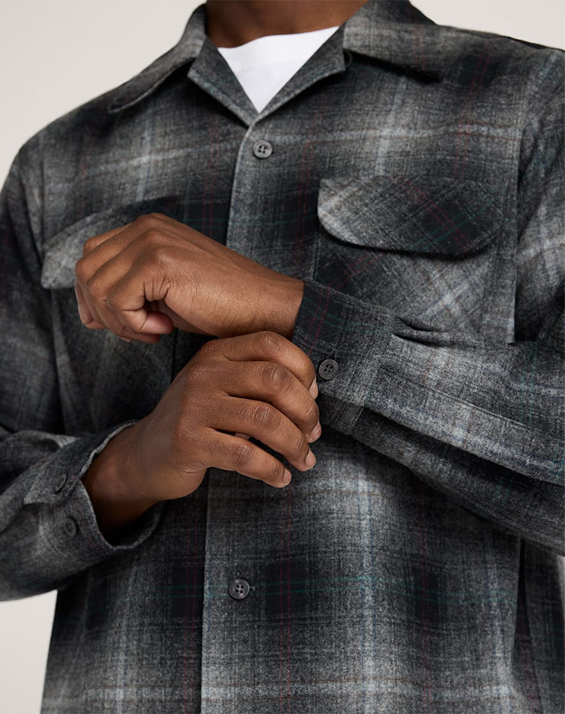 Person wearing a gray plaid shirt with a neutral background