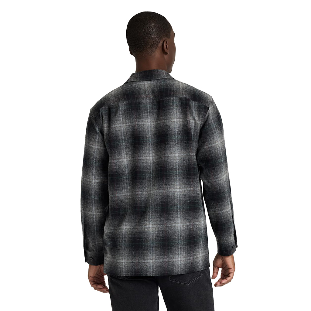 Person wearing a black and gray plaid shirt on a white background