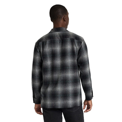 Person wearing a black and gray plaid shirt on a white background
