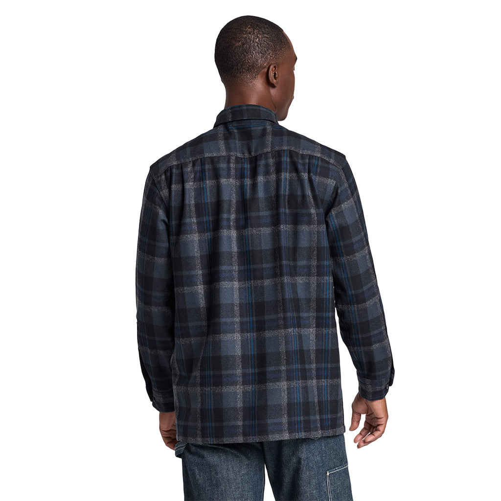 Man wearing a blue plaid shirt on a light gray background