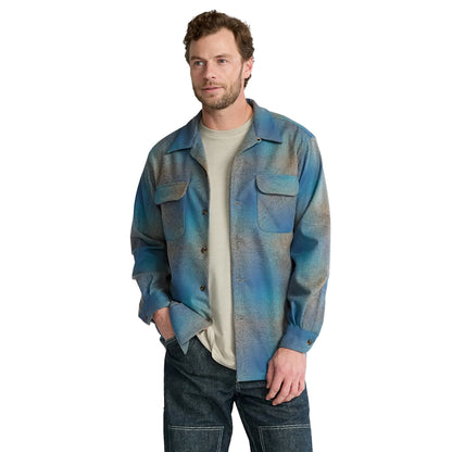 Man wearing a blue patterned shirt over a white t-shirt on a white background