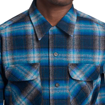Close-up of a person wearing a blue and gray plaid shirt.