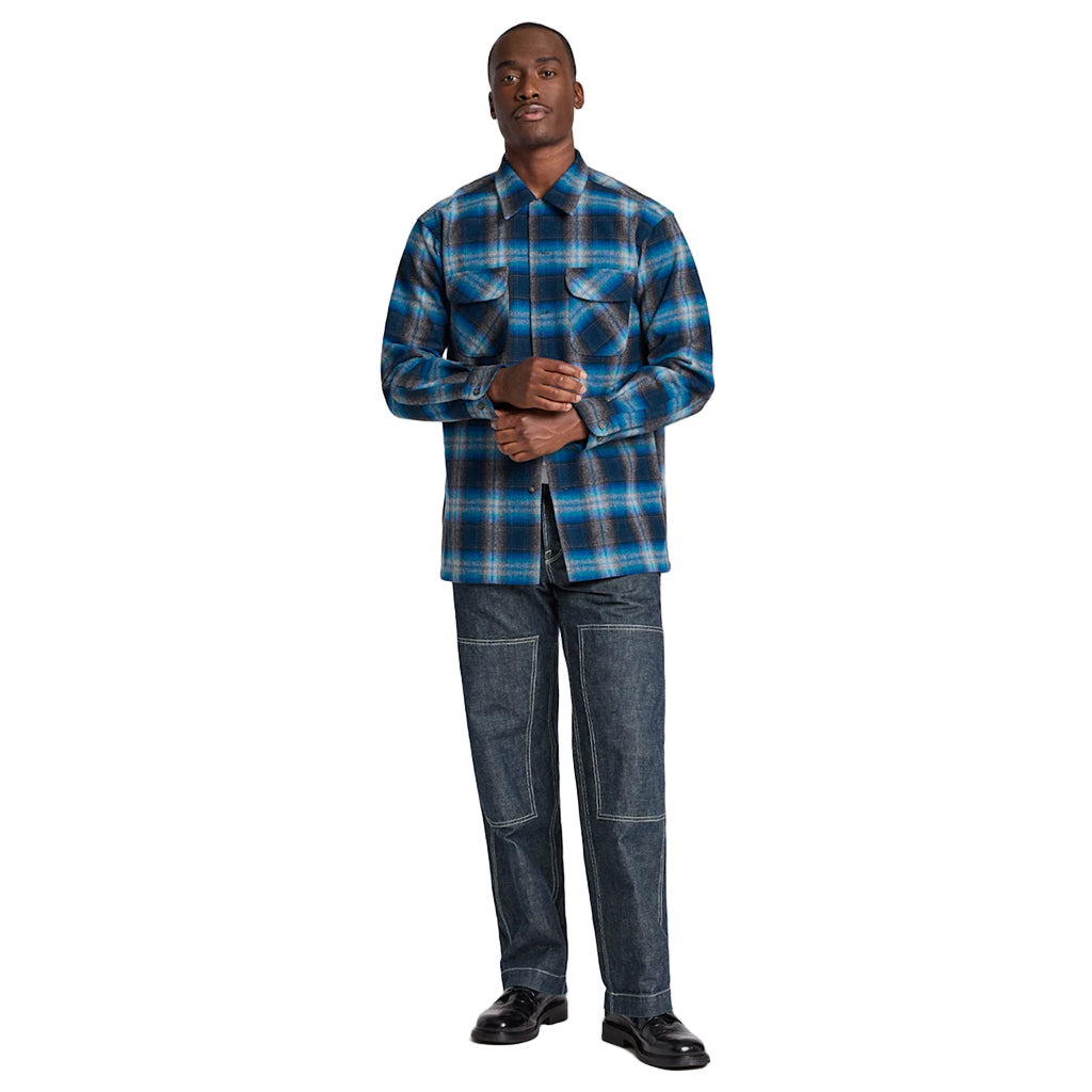 Man wearing a blue plaid shirt and jeans on a white background