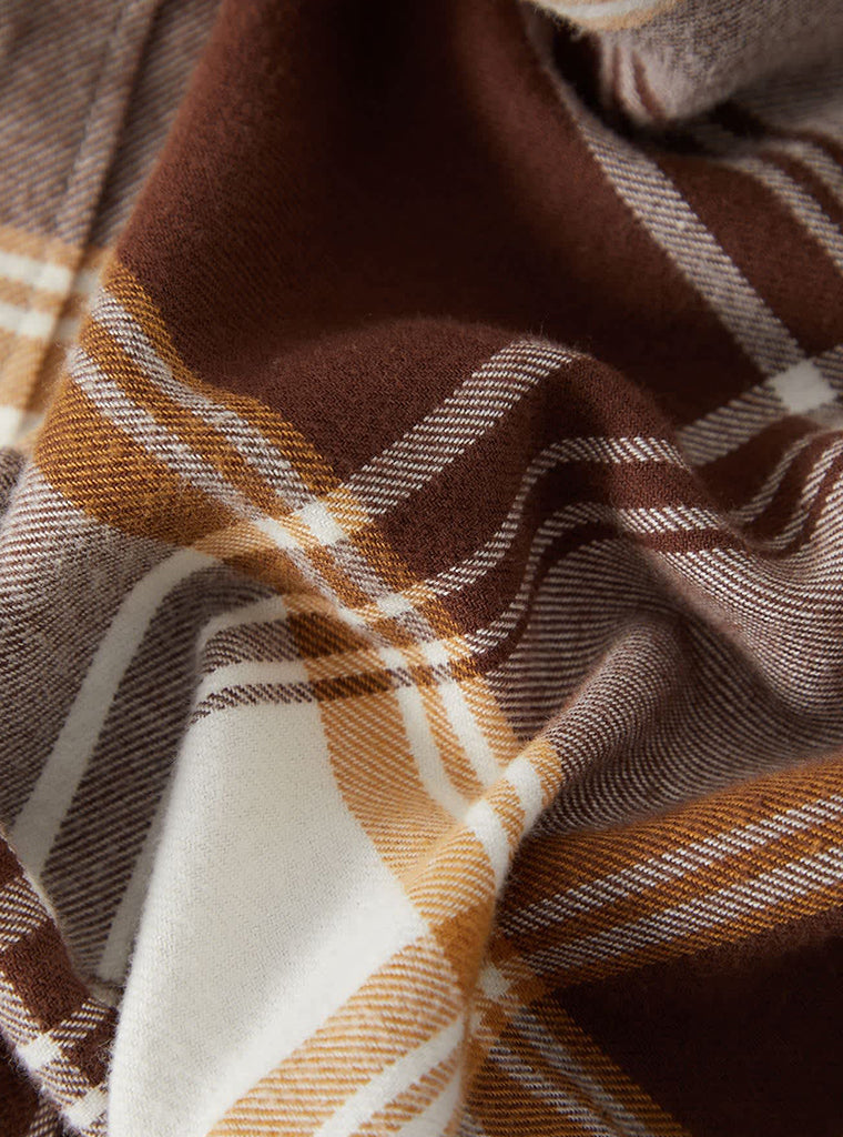 Close-up of a plaid fabric with brown, orange, and white colors.