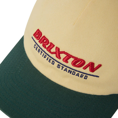 Close-up of a cap with Brixton logo on a beige and green background