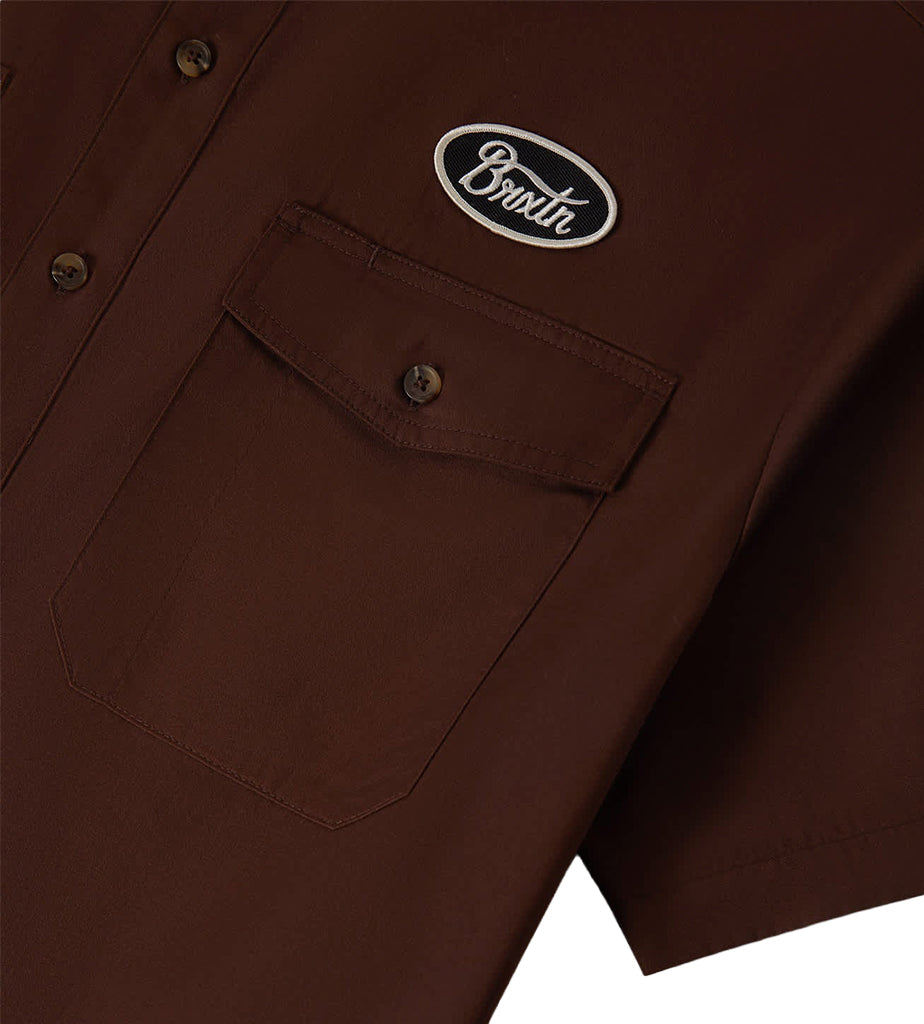 Brown shirt with a brand logo on the chest pocket against a white background