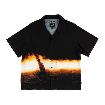 Black shirt with a printed design of a person sitting by a fire on a white background