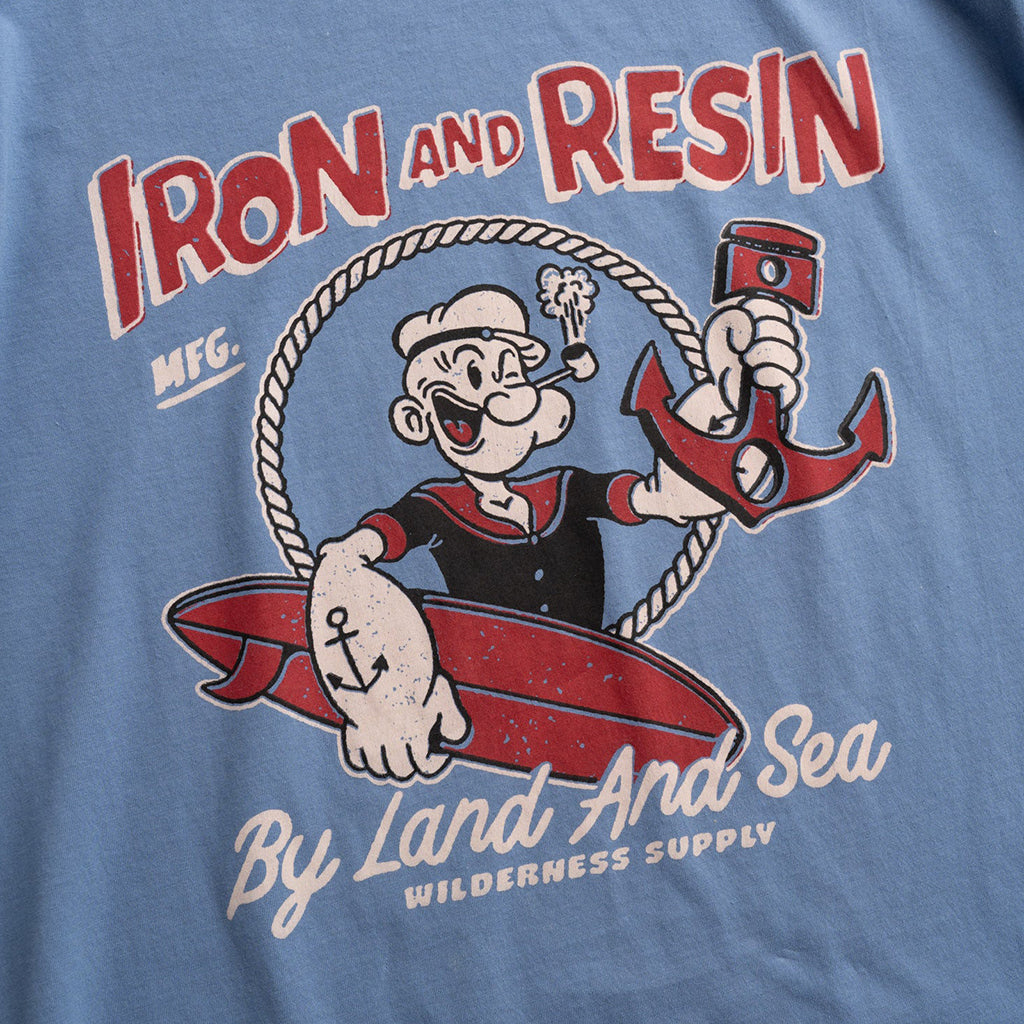 T-shirt with a cartoon character holding an anchor and text 'Iron and Resin' on a blue background