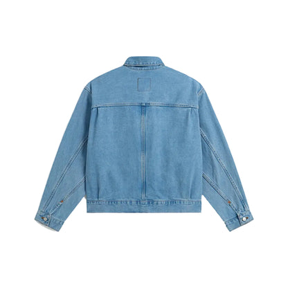 A light blue denim jacket shown from the back, featuring a buttoned collar, long sleeves, and a central seam, photographed against a solid light gray background.
