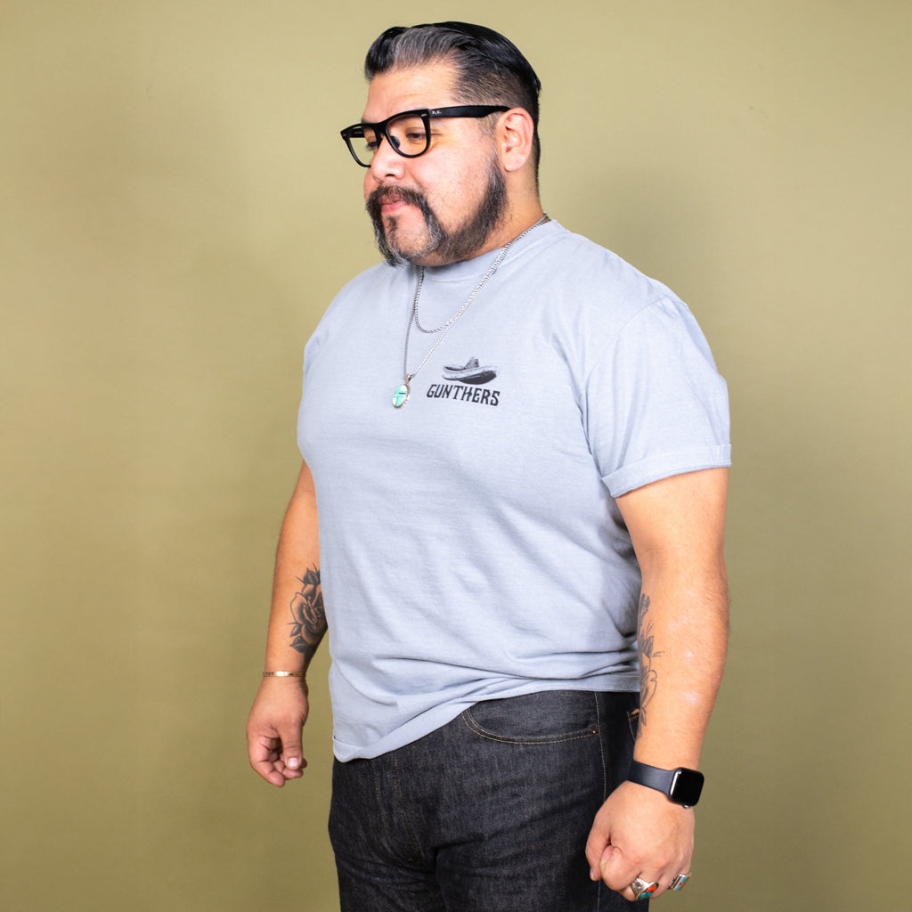Man wearing a gray t-shirt with a logo on a beige background
