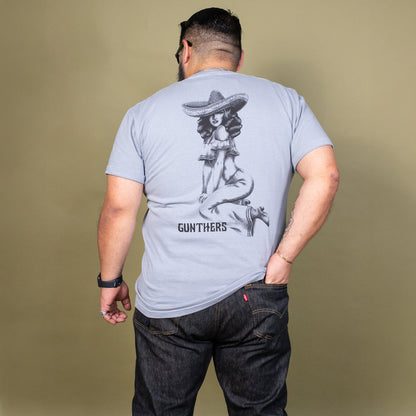 Man wearing a light blue t-shirt with a graphic design on the back against a beige background