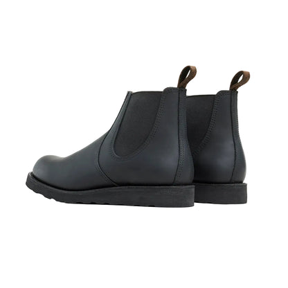 Pair of black leather Chelsea boots on a light gray background