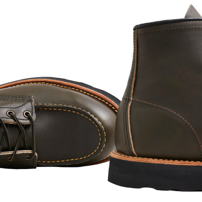 Green leather boots with black soles on a white background