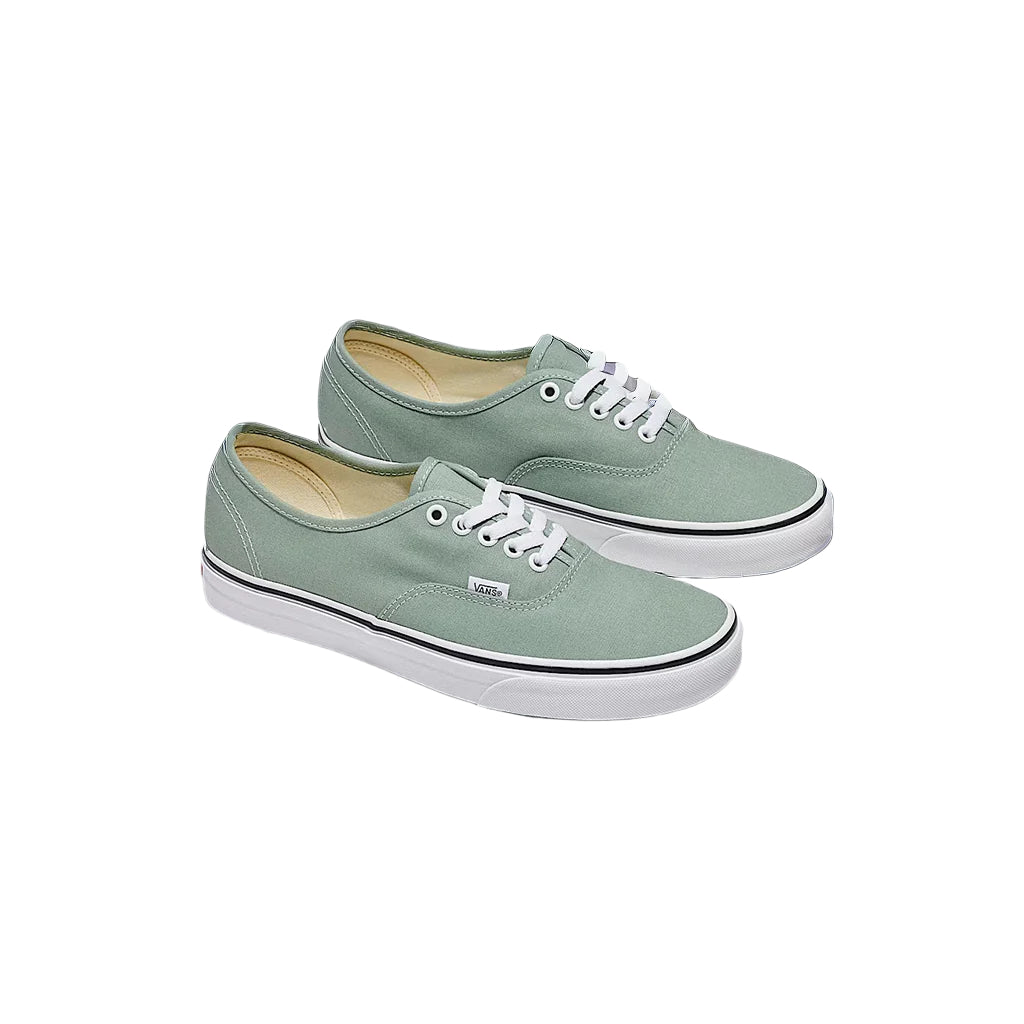 Pair of light green sneakers with white laces on a light gray background