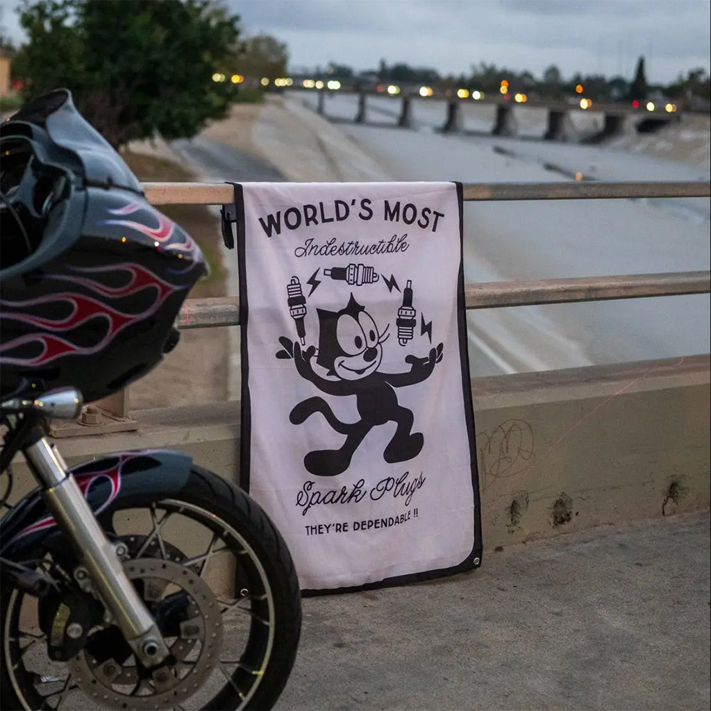 Motorcycle with a helmet and a towel featuring a cartoon character and text on a bridge.