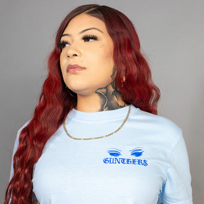 Woman wearing a light blue t-shirt with a logo and text on a gray background