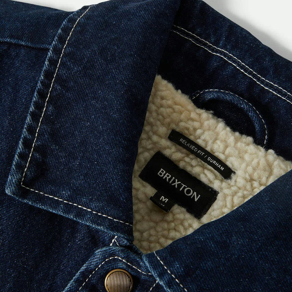 Close-up of a denim jacket with Brixton branding on a white background