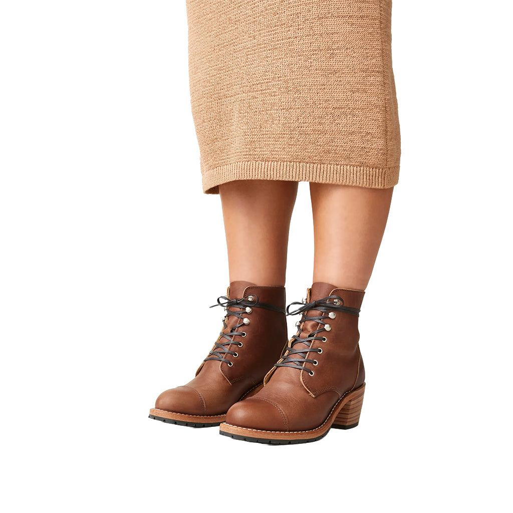 Brown lace-up boots worn with a beige skirt on a white background
