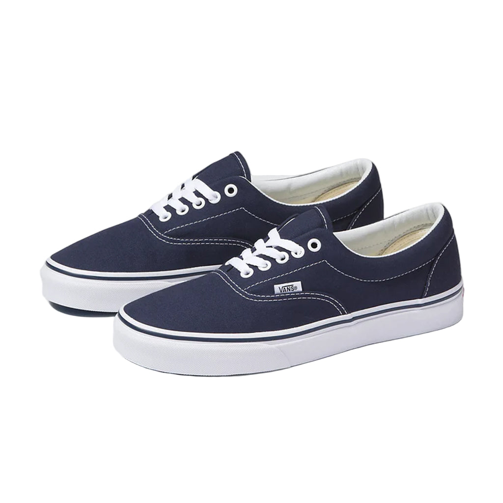 Pair of navy blue sneakers with white laces on a light gray background