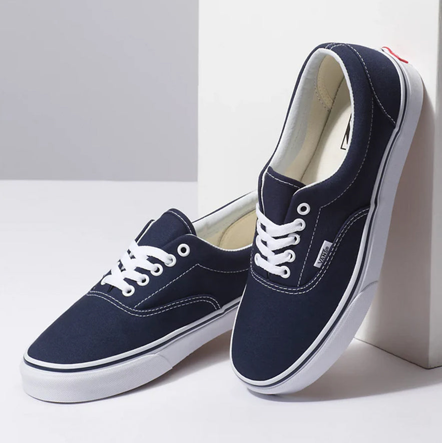Navy blue sneakers with white soles on a light gray background