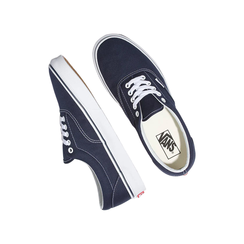 Navy blue Vans sneakers with white soles on a light gray background