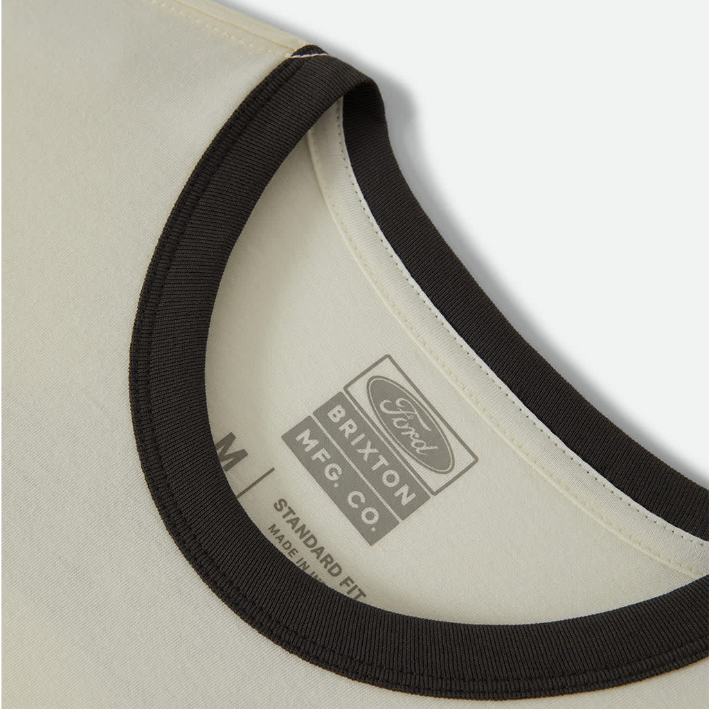 Close-up of a cream-colored shirt with a black ribbed trim, showing the inner neck label for Ford Brixton MFG. Co.