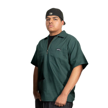 Person wearing a green shirt with a brand logo on a white background