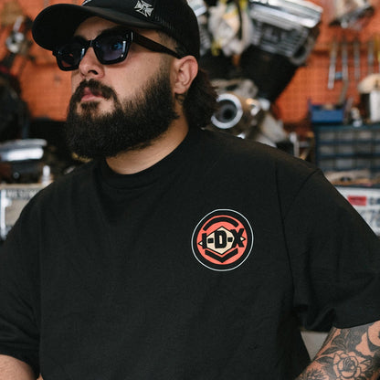 Man wearing a black t-shirt with a logo in a workshop setting