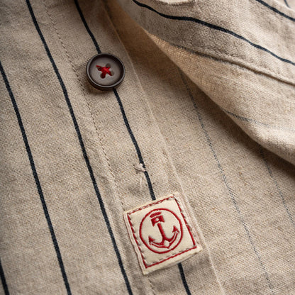 Close-up of a button on a striped fabric with a brand label featuring an anchor emblem.