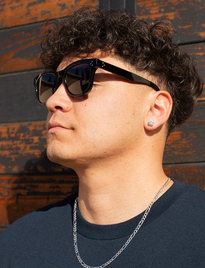 Man wearing sunglasses and a dark shirt against a rustic wooden background