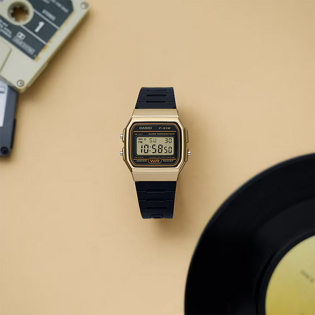 Gold Casio digital watch with black strap on a beige background