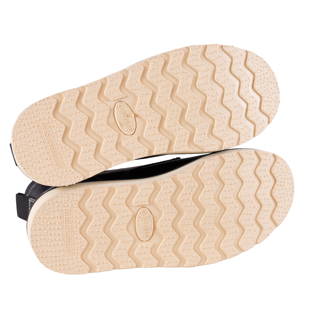 Close-up of beige shoe soles with a brand logo on a white background