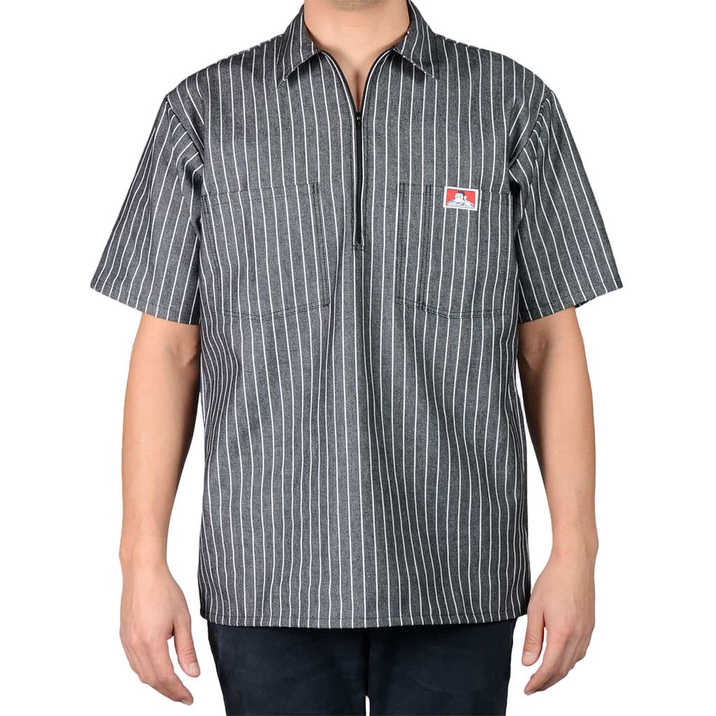 Person wearing a black and white striped shirt with a logo on a gray background