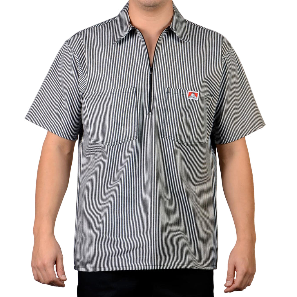 Person wearing a short-sleeve, striped shirt with a small logo on a plain background