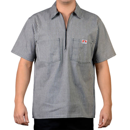 Person wearing a short-sleeve, striped shirt with a small logo on a plain background