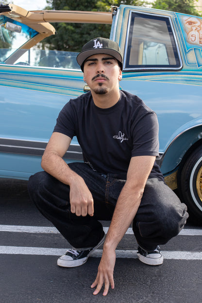 Man squatting in front of a classic car with a blue and white color scheme.