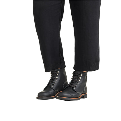Black leather boots worn with black pants on a white background
