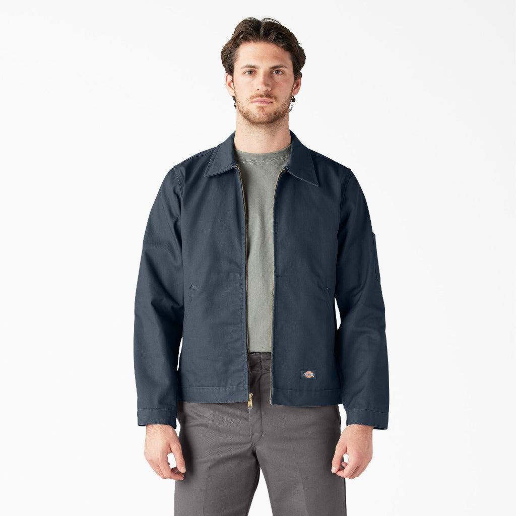 Man wearing a navy jacket over a gray shirt and pants on a white background