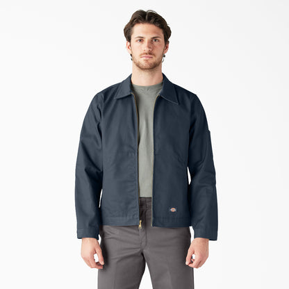 Man wearing a navy jacket over a gray shirt and pants on a white background