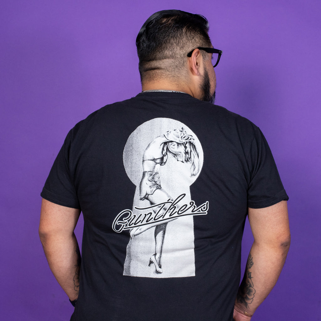 Person wearing a black t-shirt with a graphic design on the back against a purple background