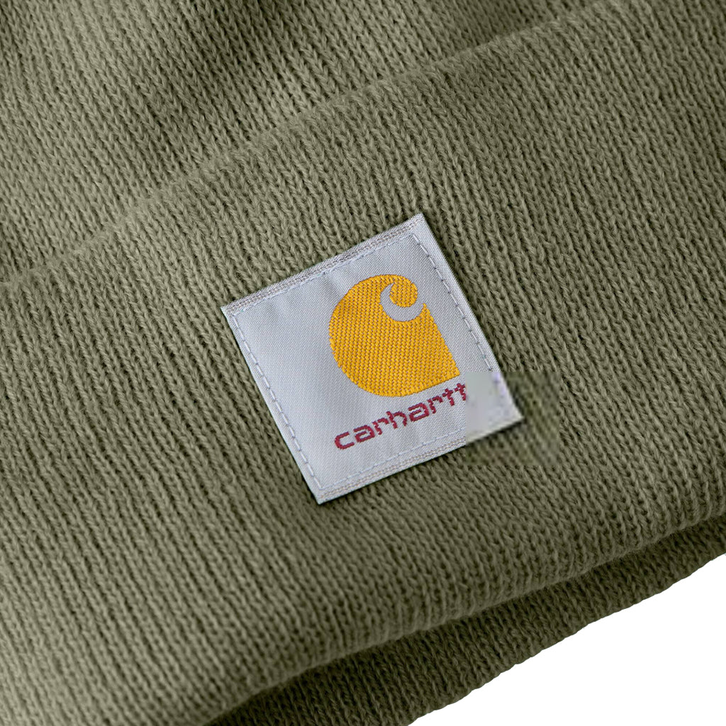 Close-up of a Carhartt logo patch on a green fabric background